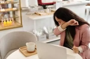 woman sneezing in arm